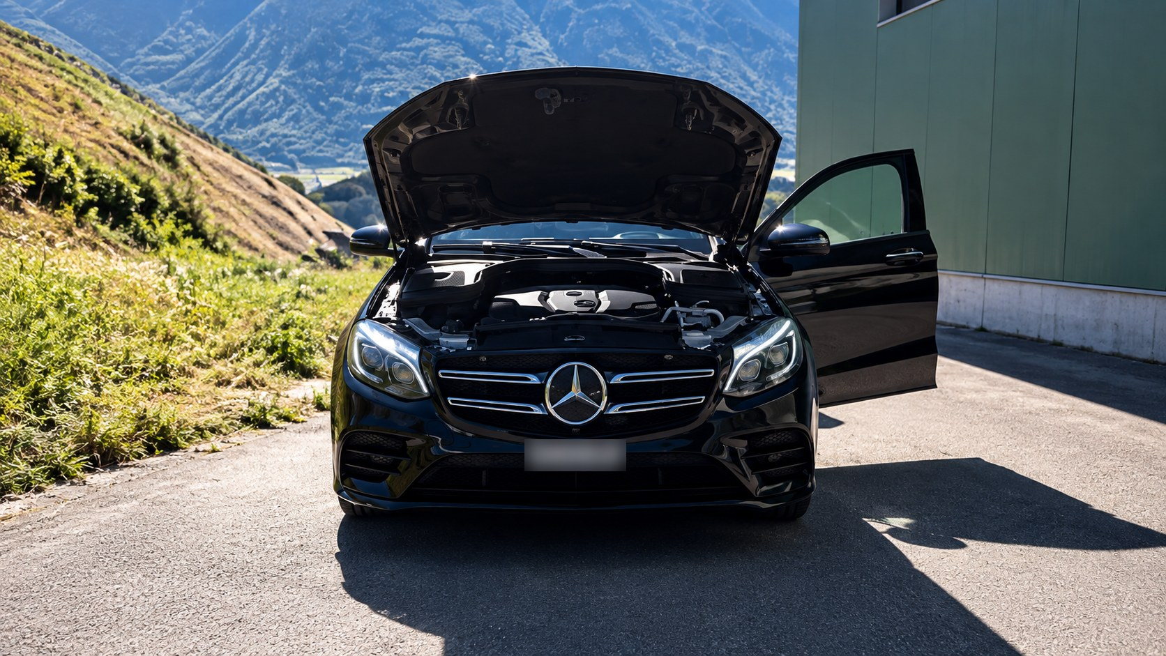 Mercedes noire capot ouvert après un nettoyage moteur par Clean Car Martigny, montagnes du Valais en arrière-plan